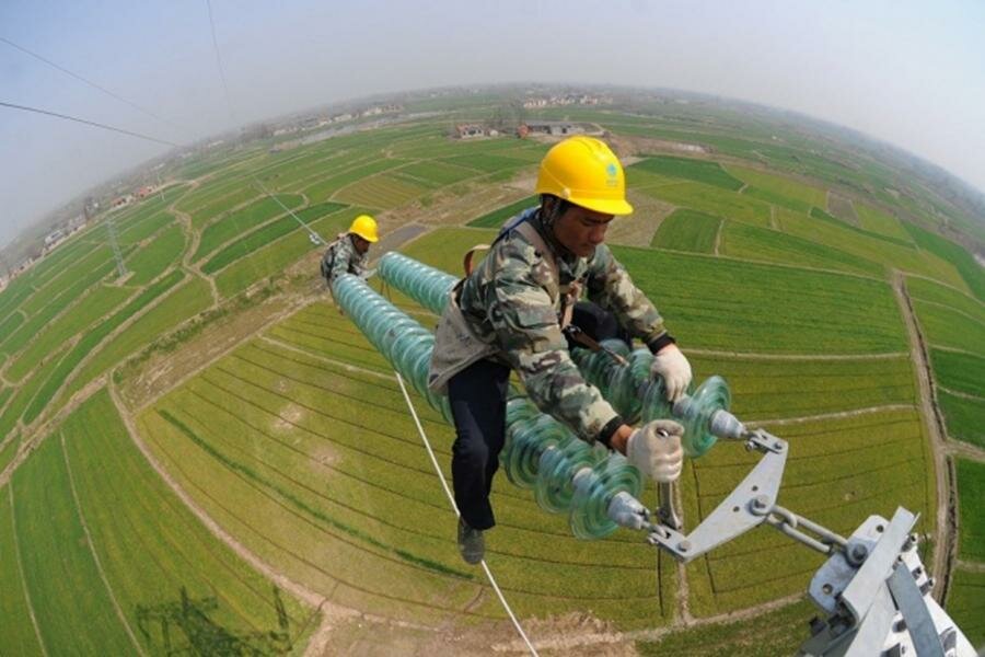 homme qui installe une ligne électrique en Chine