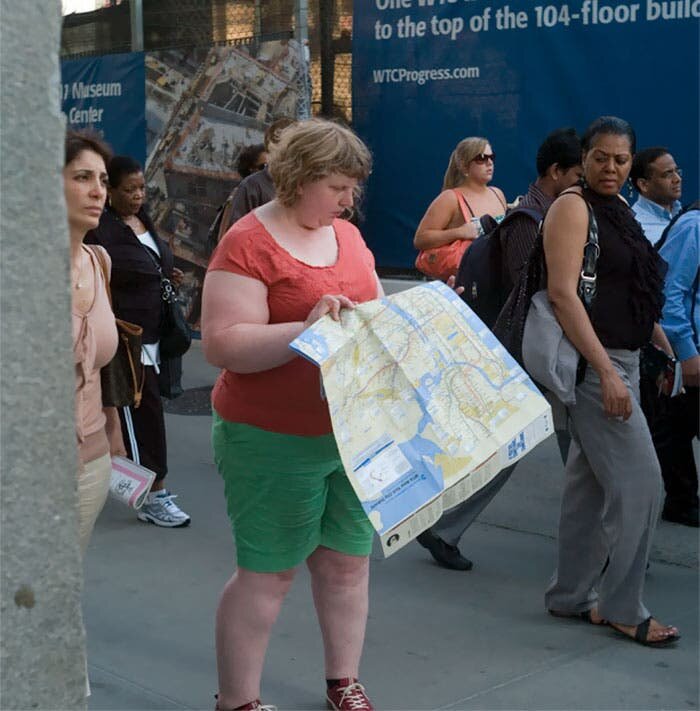 Une jeune femme dans la rue lit une carte